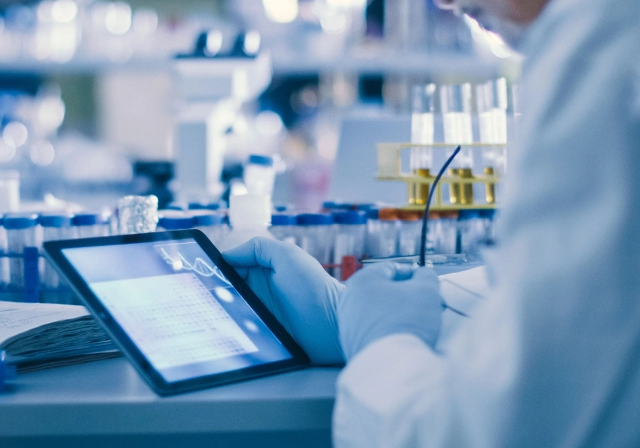 A researcher in a lab looking at a tablet.