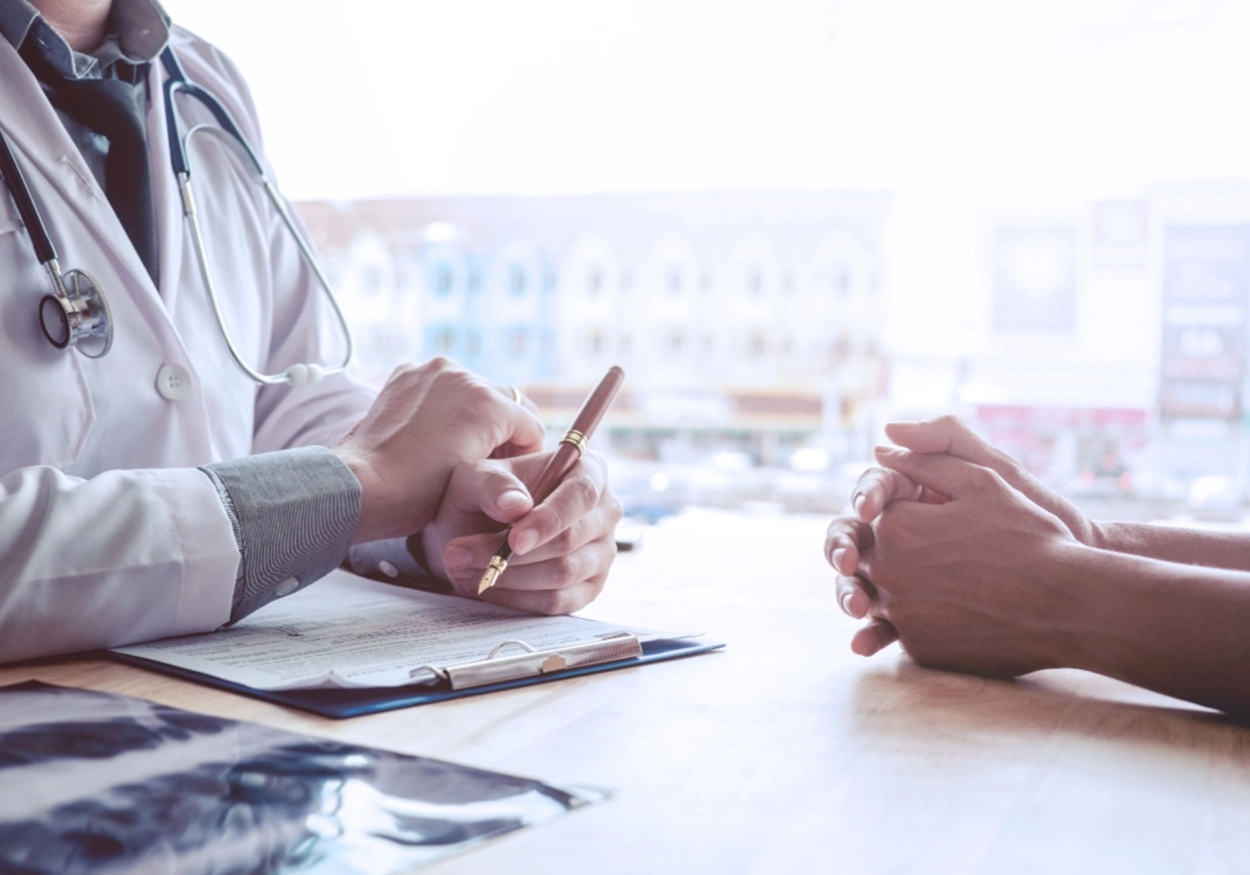 A doctor holding a pen talking to a patient.