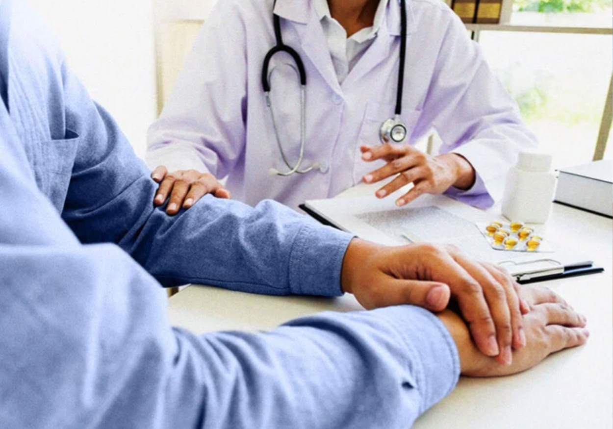 A doctor consoling a patient with their hand on the patient's arm.