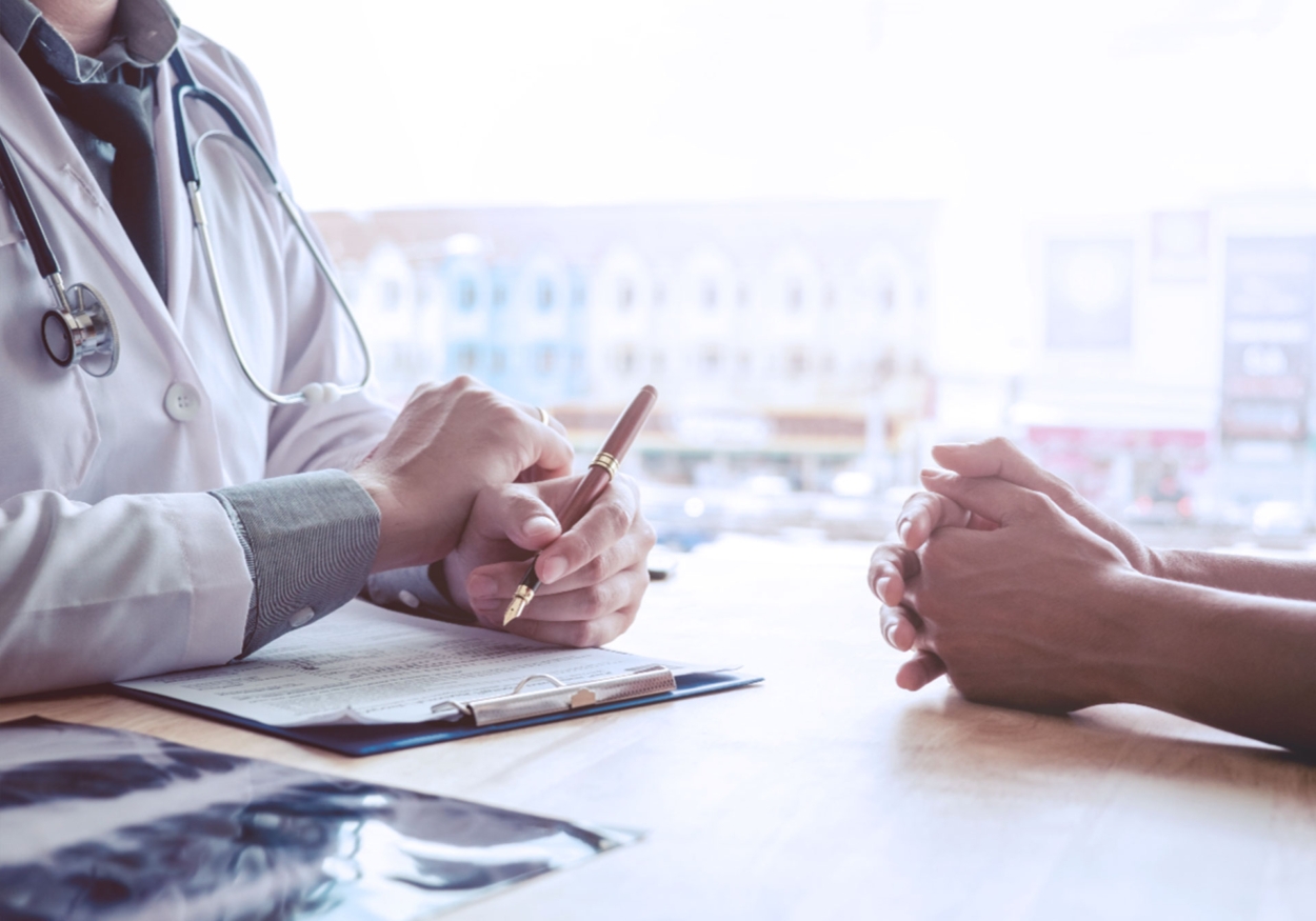 A doctor holding a pen talking to a patient.