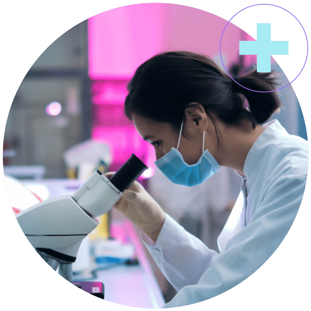 A researcher in a lab looks into a microscope.